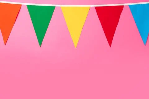Bunting with colorful triangular flags on pink background. Space for text Stock Photos