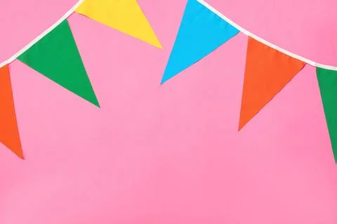 Bunting with colorful triangular flags on pink background. Space for text Stock Photos