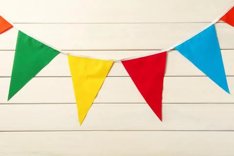 Bunting with colorful triangular flags on white wooden background. Festive de Stock Photos