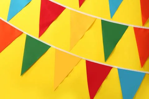 Bunting with colorful triangular flags on yellow background. Festive decor Stock Photos