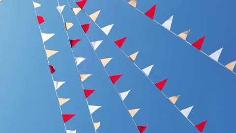 Bunting flags creating a festive atmosphere against a clear blue sky on a sunny Stock Footage 348214211