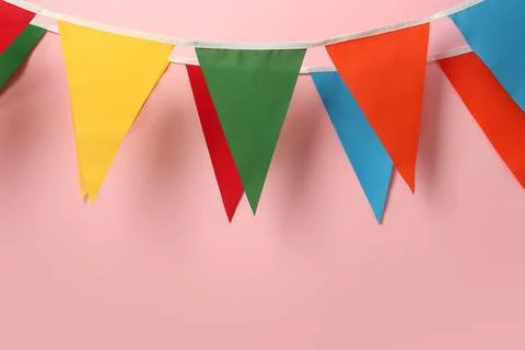 Buntings with colorful triangular flags hanging on pink background. Festive d Foto stock