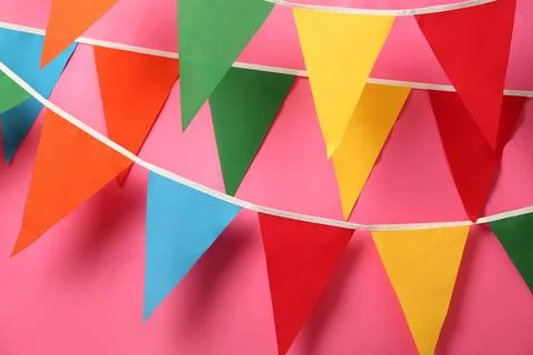Buntings with colorful triangular flags hanging on pink background. Festive d Foto stock