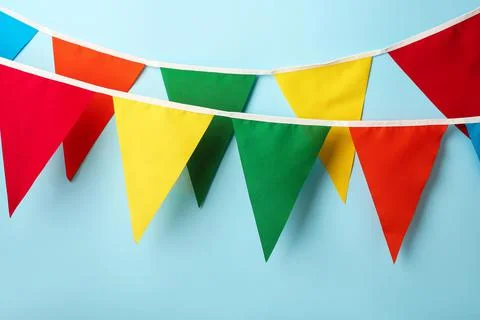 Buntings with colorful triangular flags hanging on light blue background. Fes 写真素材