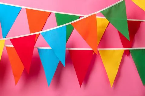Buntings with colorful triangular flags hanging on pink background. Festive d Foto stock