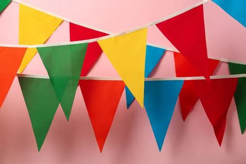 Buntings with colorful triangular flags hanging on pink background. Festive d Foto stock