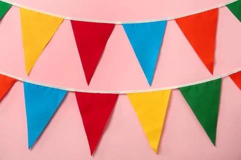 Buntings with colorful triangular flags on pink background. Festive decor Stock Photos