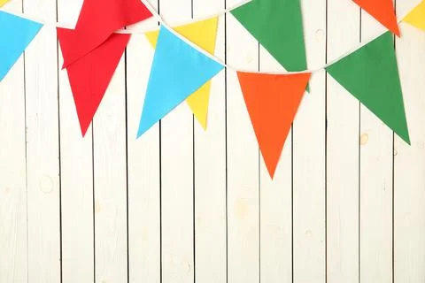 Buntings with colorful triangular flags on white wooden background. Space for Stock Photos