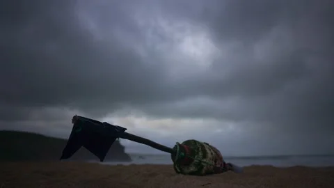 A buoy with a flag flying in the wind lying on the northern beach of Nazare Stock Footage 230155562