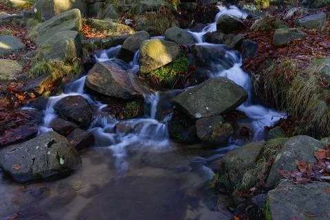Burbage Brook flows quickly down a slope over rocks in Padley Gorge. Stockfoto's