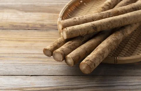 Burdock in a bamboo colander placed in the background of a wooden board Stock Photos