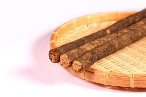 Burdock root with soil on a bamboo colander Stock Photos
