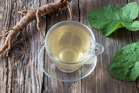 Burdock tea and root on a table Stock Photos