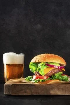 Burger and beer, a side view on a dark background with copy space. Selective Stock Photos
