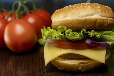 Burger and tomatoes on the table. Making burgers at home. Fast food. Stock Photos