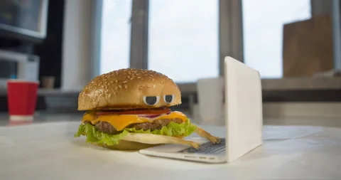 Burger animated character with eyes using laptop, notebook. Fast food online Stock Footage 233178857