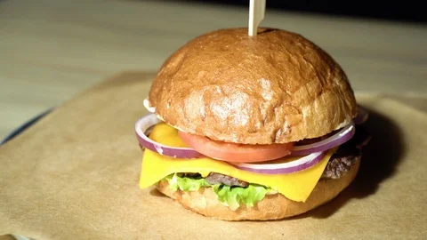 Burger with beef cutlet, lettuce, tomato, onion served on pieces of paper Stock Footage 113604945