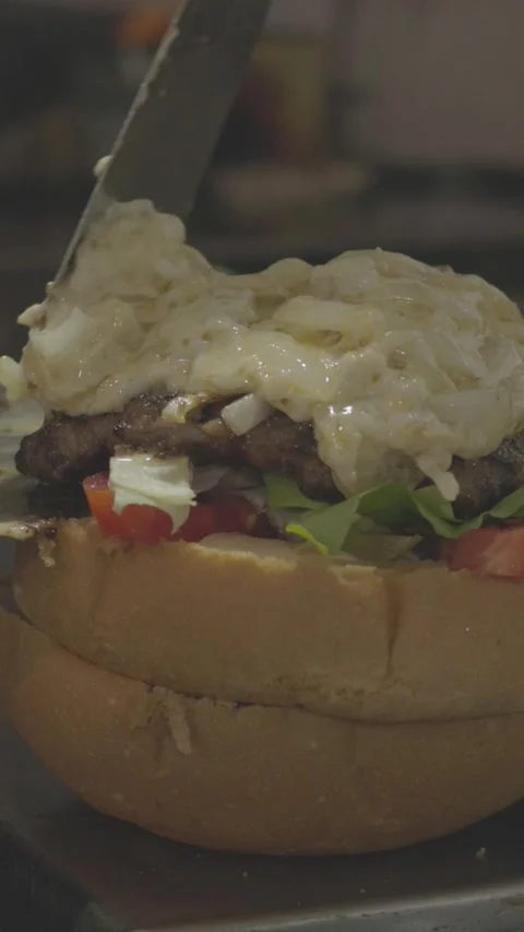 Burger being stacked with melted cheese, vegetables and beef patty on bun Video stock 305795460