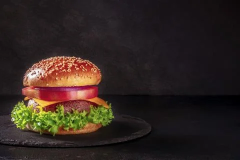 Burger on a black background with a place for text. Beef patty steak with a Stock Photos