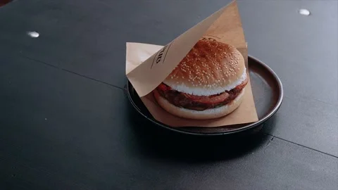 Burger on a ceramic tray. appetizing burger wrapped in cardboard paper Stock Footage 137896583