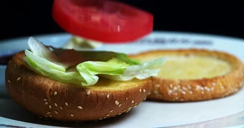 Burger cooking HD slow motion video. Hamburger ingredients falls bread bun Stock Footage 70004097