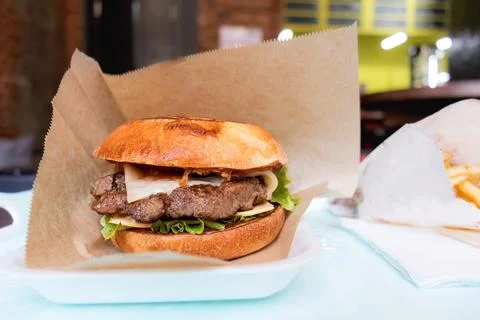 Burger in craft packaging on a table in a cafe, close-up Stock Photos
