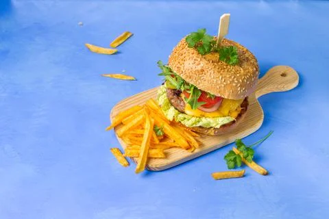 Burger with cutlet, cheese, mixed salad and red onion, on a wooden board with Stock Photos