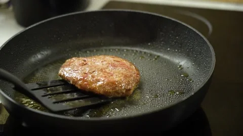 Burger cutlet is turned over with spatula and fried in frying pan Vidéo 232780258