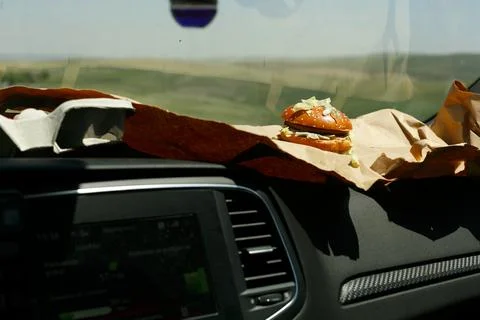 A burger on the dashboard hints at a journey, probably on a highway, with fas Stock Photos