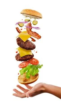 Burger falling into customer's hand. Creative shot of flying ingredients Stock Photos