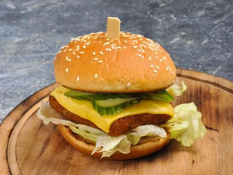 Burger with fish cutlet, cucumber, cheese and lettuce Stock Photos