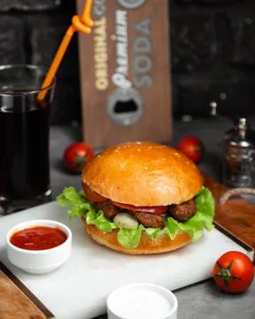 Burger with fried cotlet, cabbage and tomato served with ketchup and mayonnaise Stock Photos