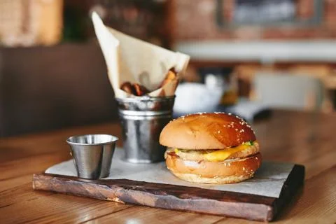 Burger with fried potatoes on the table in restaurant Stock Photos