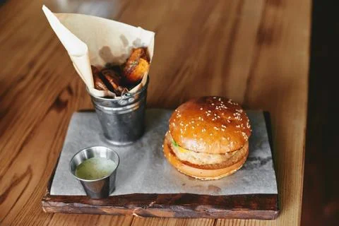 Burger with fried potatoes on the table in restaurant Stock Photos