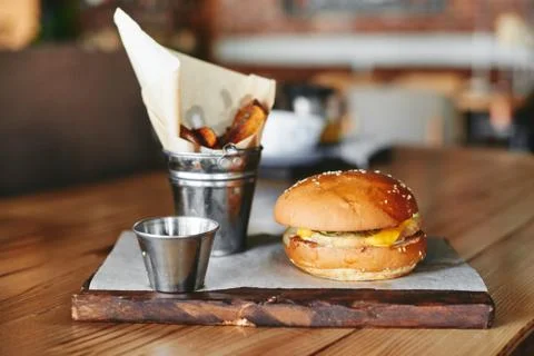 Burger with fried potatoes on the table in restaurant Stock Photos