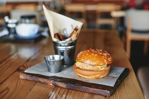 Burger with fried potatoes on the table in restaurant Stock Photos