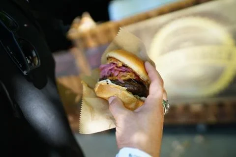 Burger in hand with red and white onions Stock Photos