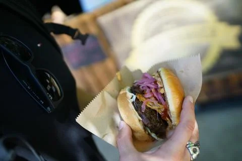 Burger in hand with red and white onions at a foodfestival Stock Photos