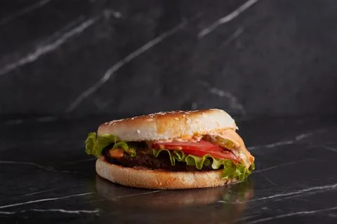 Burger with meat and cheese on the table, american cuisine, close-up, tomato Stock Photos