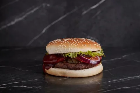 Burger with meat and cheese on the table, american cuisine, close-up, tomato Stock Photos