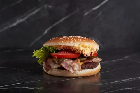 Burger with meat and cheese on the table, american cuisine, close-up, tomato Stock Photos