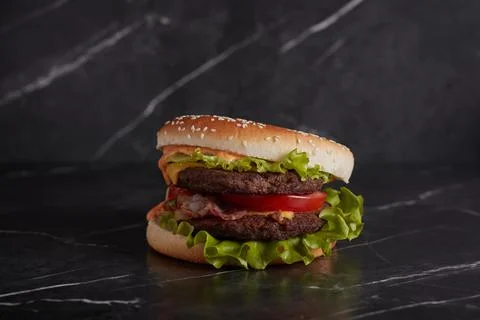 Burger with meat and cheese on the table, american cuisine, close-up, tomato Stock Photos