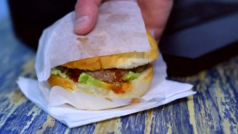 Burger with meat, vegetables and sauce on the table. Womans hand takes  sandwich Stock Footage 150998615