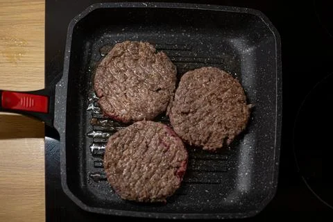 Burger minced beef meat cutlet on a grill pan. Process of cooking self made b Stock Photos