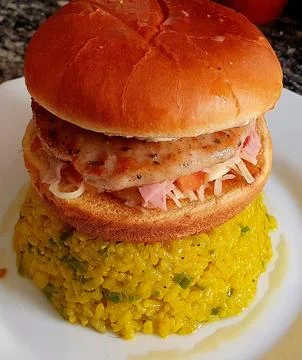 Burger on a mountain of rice cooked with curry. 库存照片