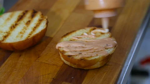 Burger sauce is applied to the loaf Stock Footage 98991138