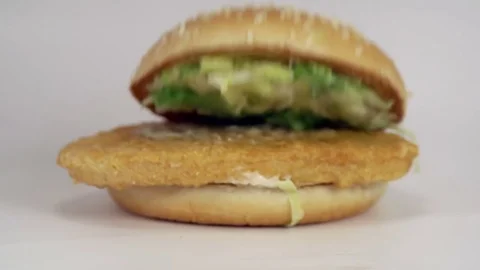 Burger with seeded bun falling onto a white background. Filmed in slow motion Stock Footage 72622627