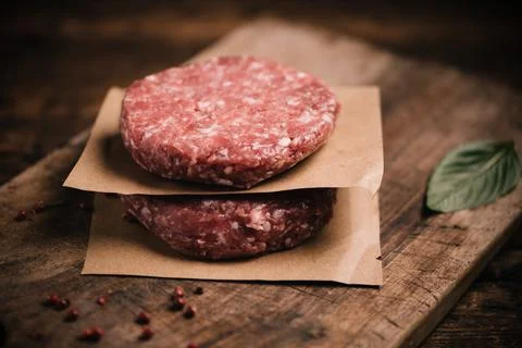 Burger steak cutlets ready to prepare on rustic table Stock Photos