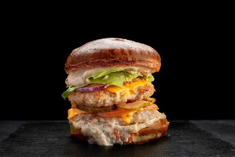 Burger with two chicken cutlets, cheese, pickle, cheese, sauce and tomatoes Stock Photos