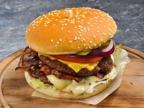 Burger with two cutlets, bacon, vegetables and cheese Foto stock